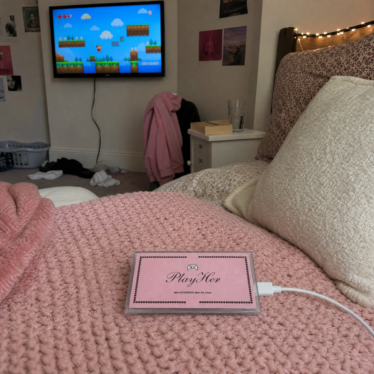 PlayHer console on a bed with a game on the TV